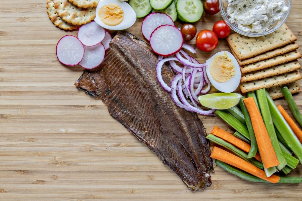 Smoked rainbow trout on board with vegetables