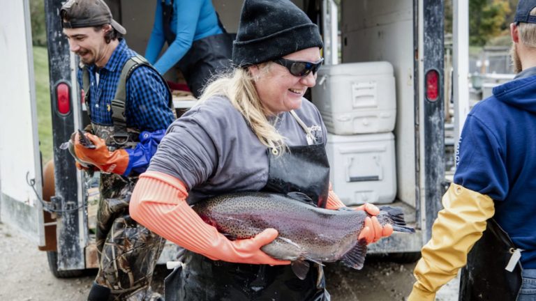 fish farmer woman holding rainbow trout