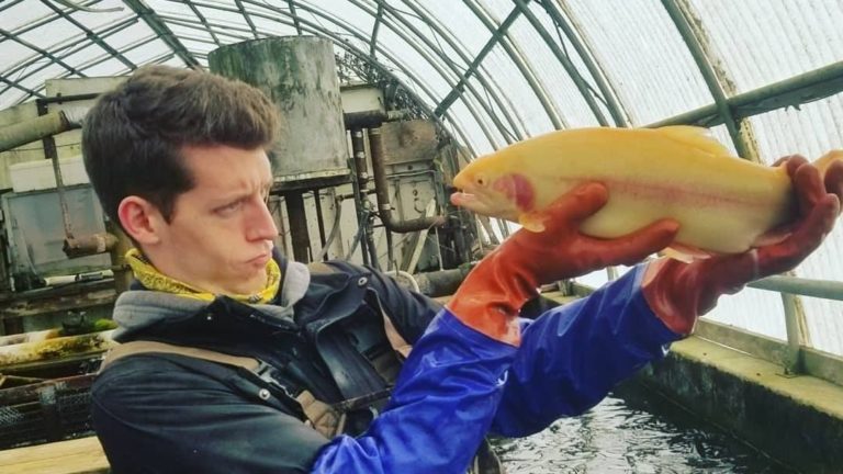 man posing with orange albino rainbow trout