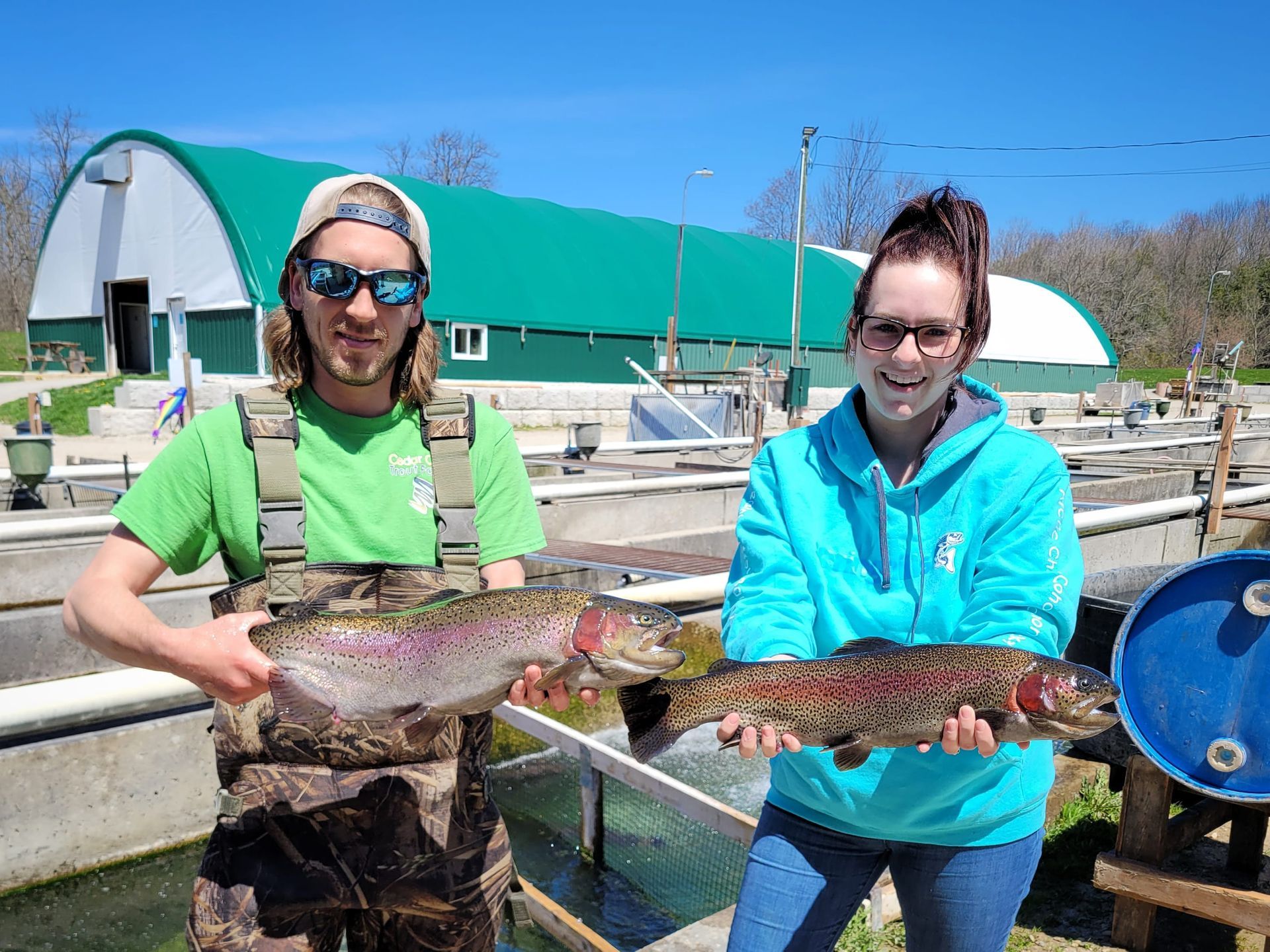 man and woman with live rainbow steelhead trout on fish farm
