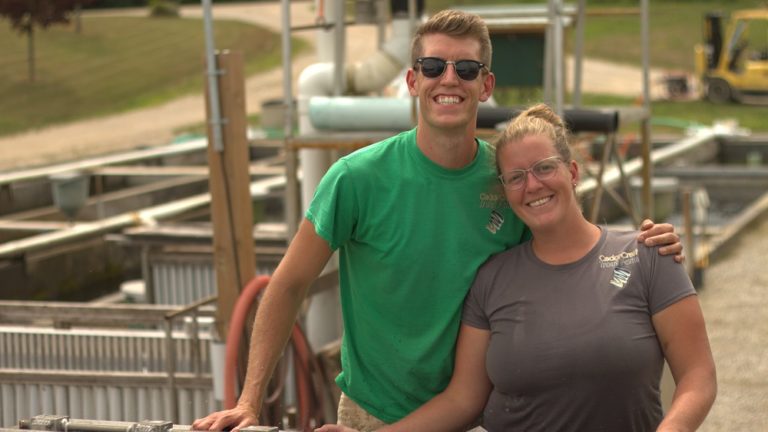 sibling fish farmers pose on farm