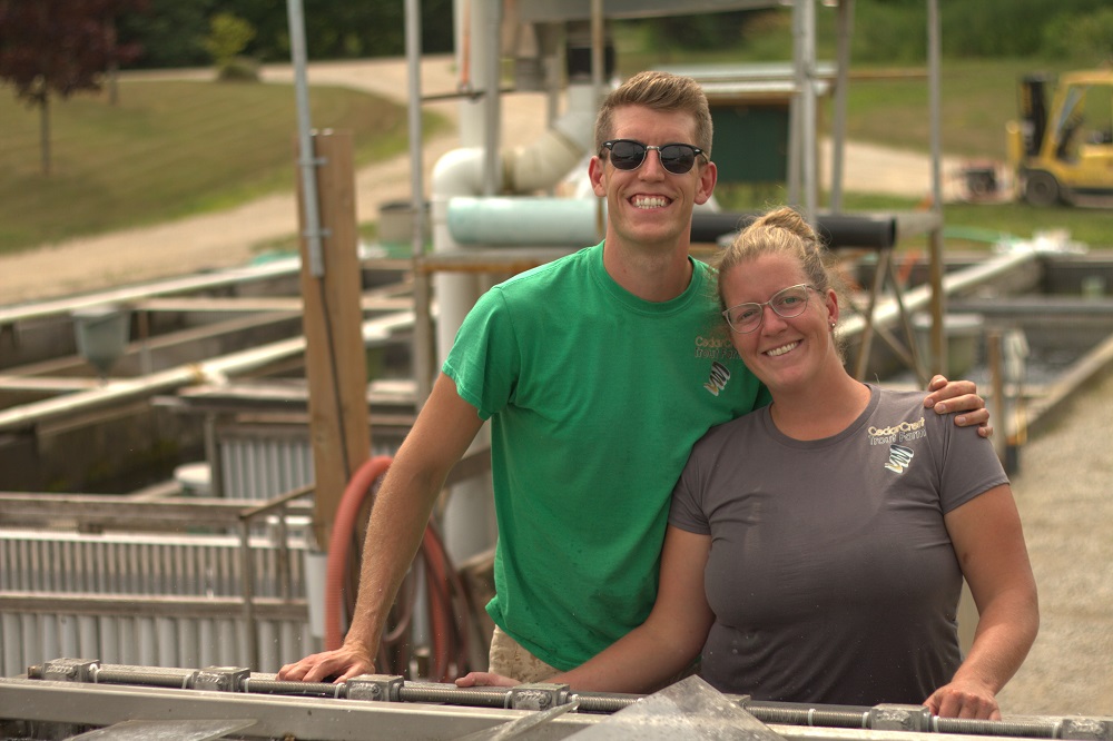 sibling fish farmers pose on farm