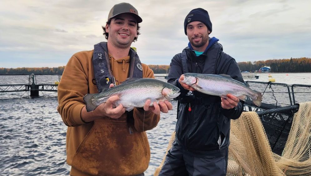 Two fish farmers holding salmon trout